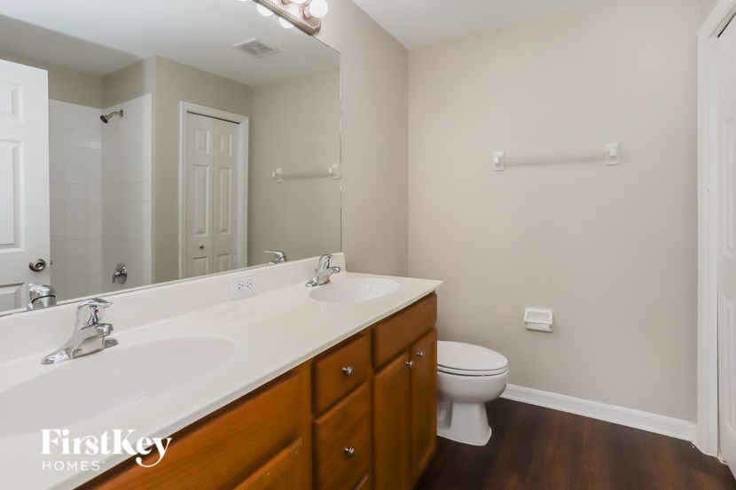 A bathroom with a toilet, sink, and mirror.