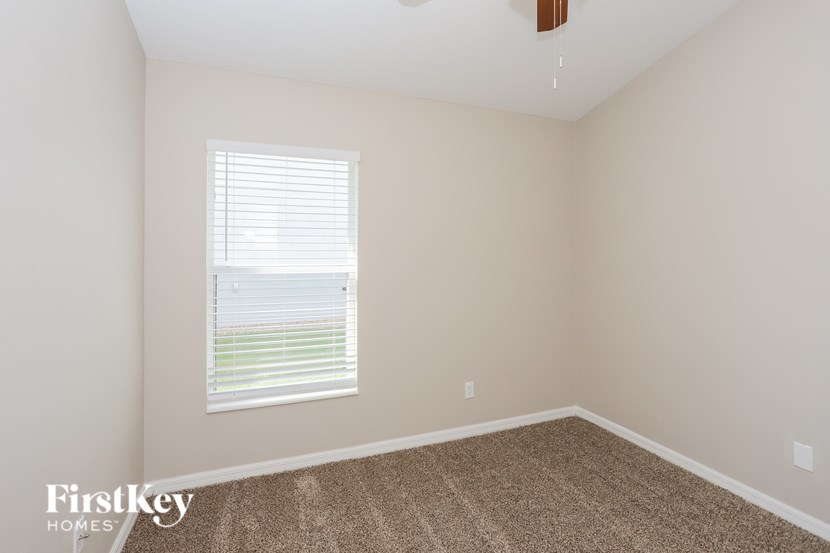 A room with a window and a carpeted floor.