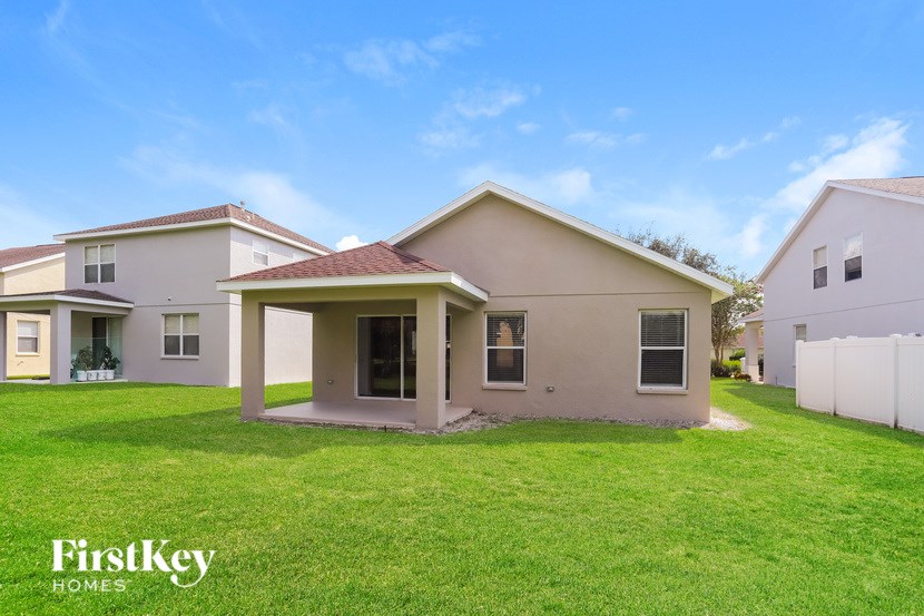 A house with a lawn in front of it and a fence in the background.
