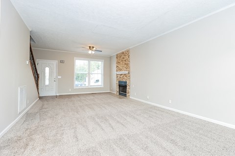 an empty living room with carpet and a fireplace