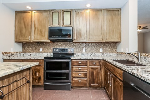 a kitchen with granite counter tops and wooden cabinets