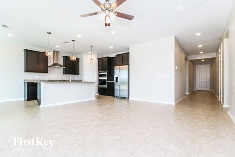 A spacious kitchen with a bar area and a ceiling fan.