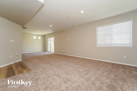 an empty living room with carpet and a window