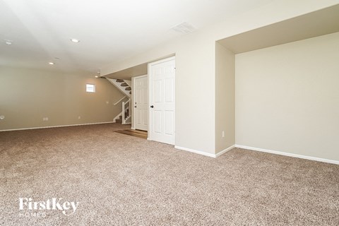 an empty living room with a door to a staircase