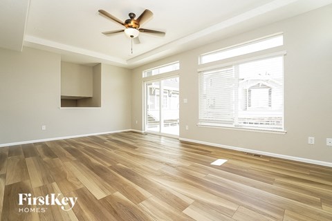an empty living room with wood floors and a ceiling fan
