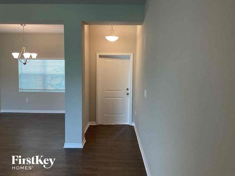an empty living room with a white door and a hallway with wood floors