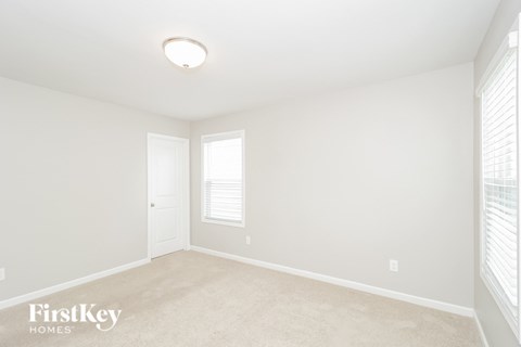 a bedroom with white walls and white carpet and a white door and window