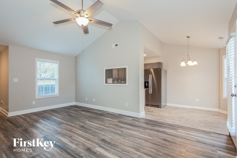 the living room and dining room of an empty house with a ceiling fan