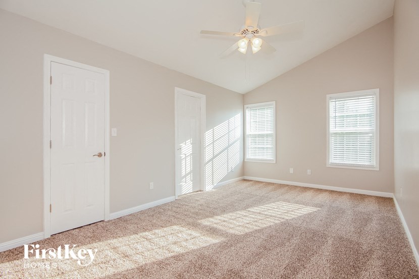 an empty living room with a ceiling fan and a window