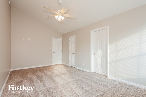 a spacious living room with carpet and a ceiling fan
