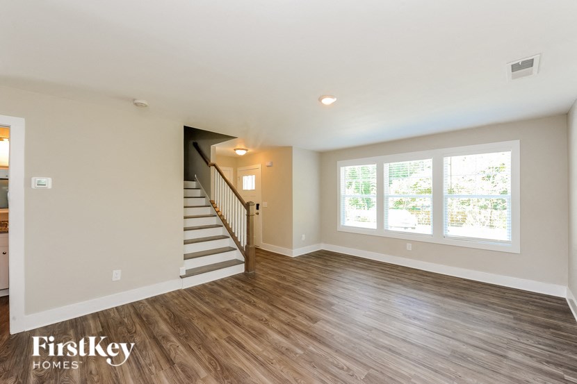 A spacious room with wooden flooring and a staircase leading to another level.