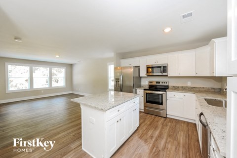 A kitchen with white cabinets and a wooden floor.