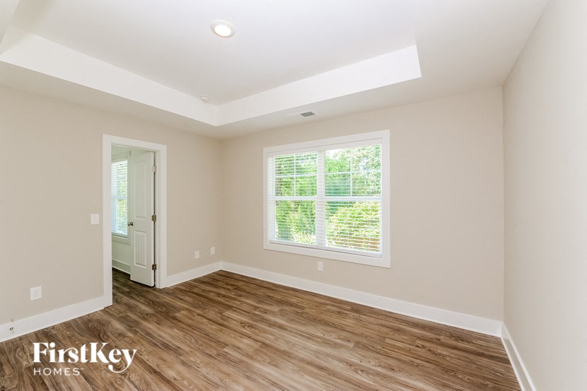 A room with a wooden floor and a window with blinds.