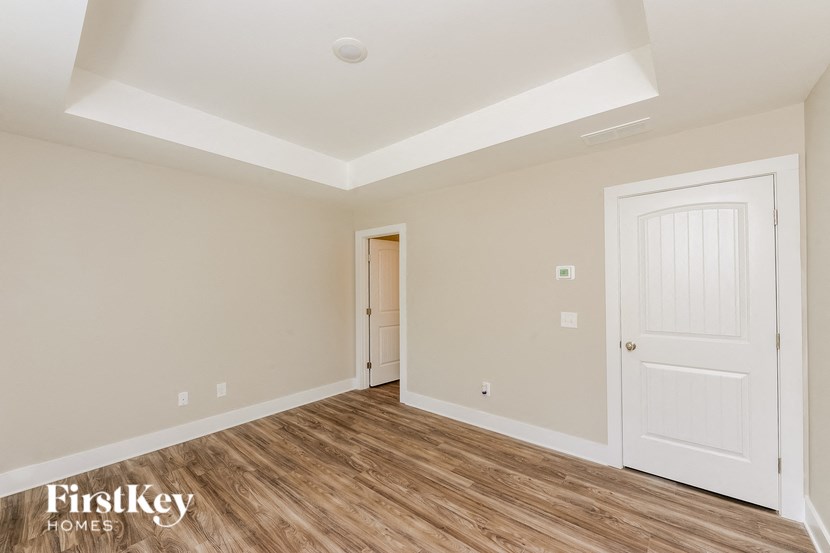 A room with a white door and a wooden floor.
