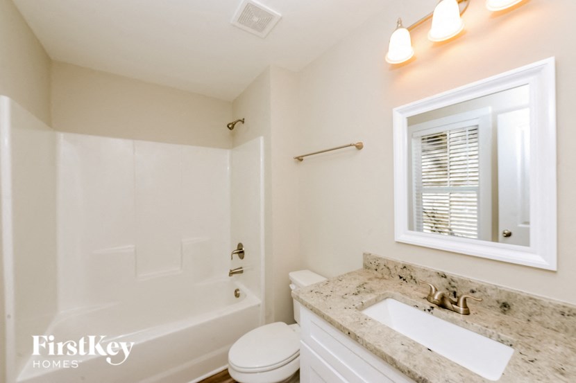 A bathroom with a white toilet, sink, and tub.
