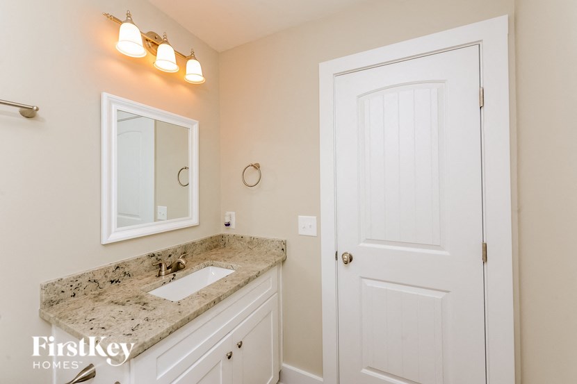 A bathroom with a granite countertop and a white door.