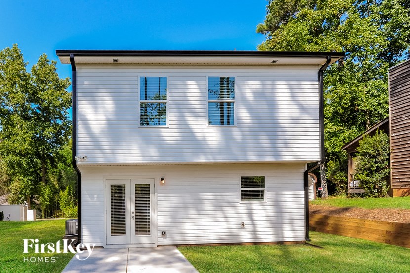 A white house with a black roof and a sign that says "FirstKey Homes".