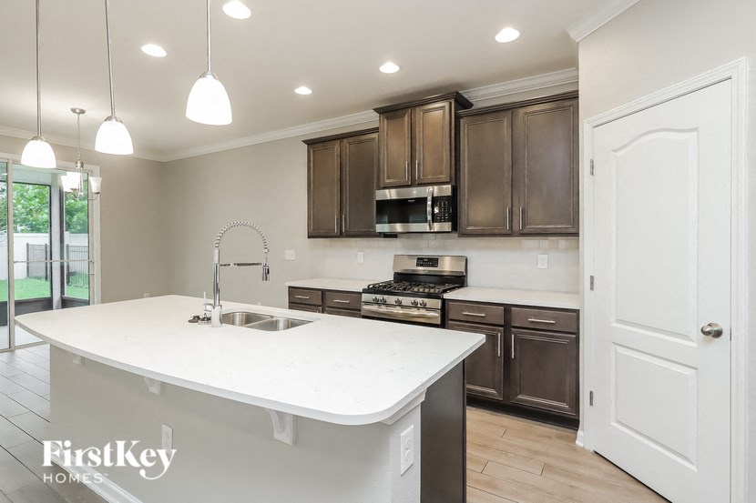 A modern kitchen with a white island and dark brown cabinets.