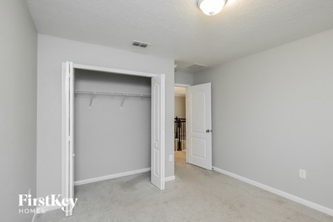A white bedroom with a large open closet door.