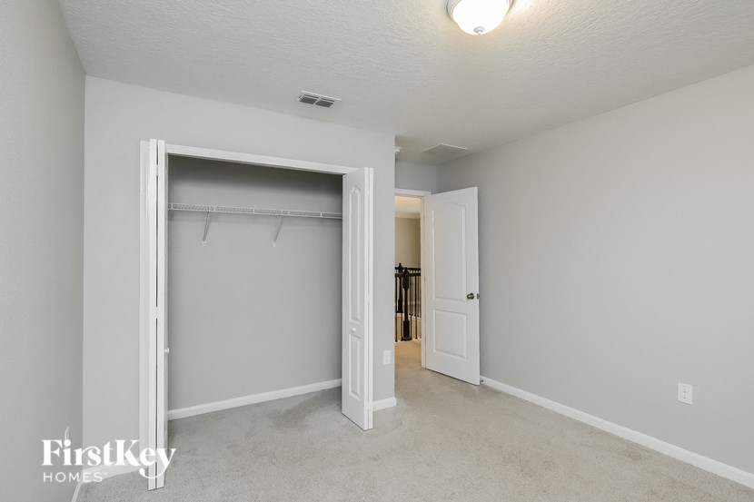 A white bedroom with a large open closet door.