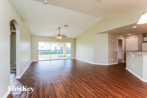 A spacious room with wooden floors and a ceiling fan.
