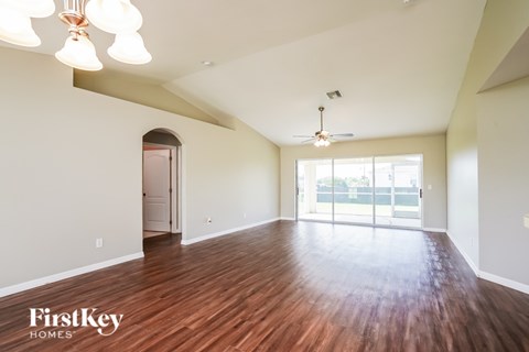 A spacious room with wooden floors and a ceiling fan.
