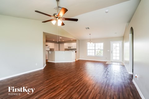 A spacious room with a ceiling fan and wooden flooring.