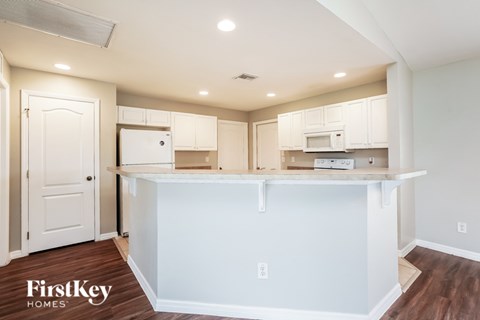 A kitchen with white cabinets and a white island.