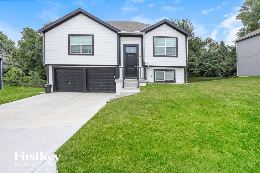 a white house with a green lawn and a driveway