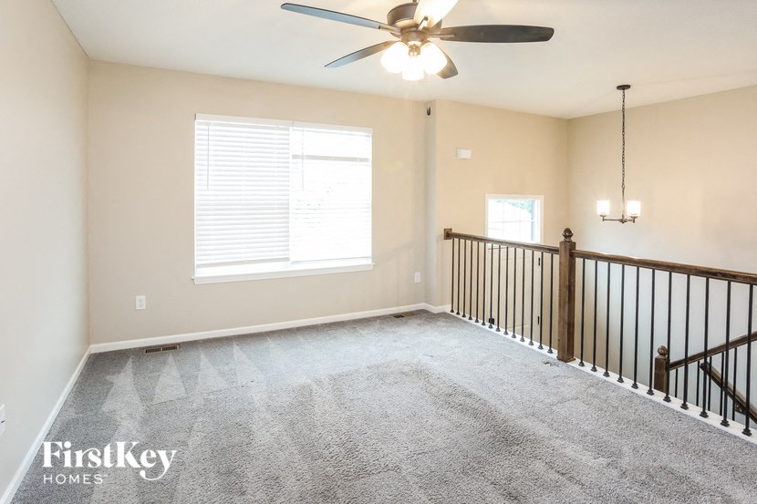 an empty living room with a ceiling fan and a railing