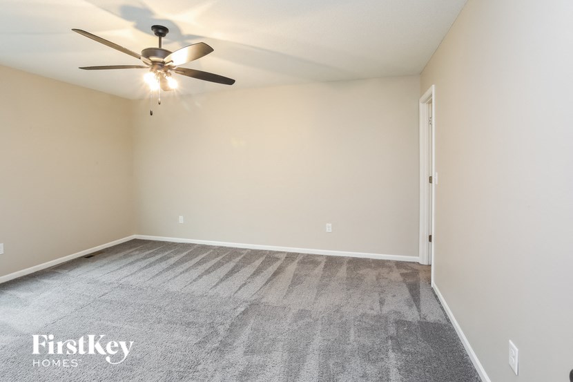 a empty living room with a ceiling fan and carpet