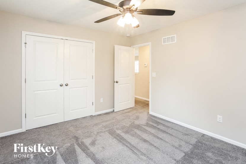 an empty living room with a ceiling fan and white doors