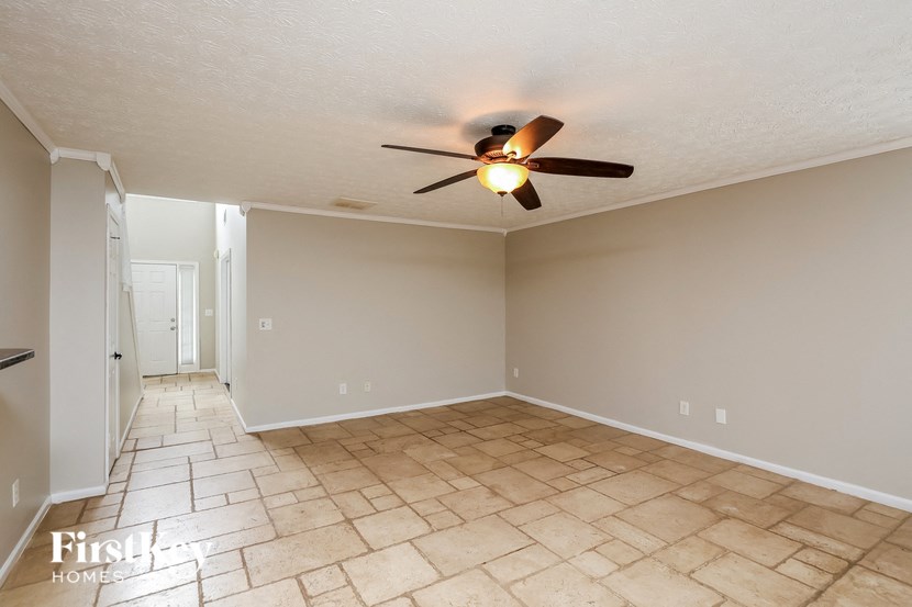 a empty living room with a ceiling fan and a tiled floor