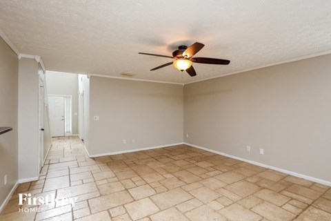 a empty living room with a ceiling fan and a tiled floor