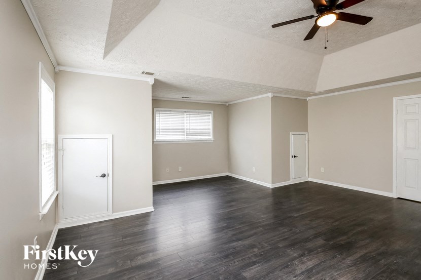 an empty living room with wood floors and a ceiling fan