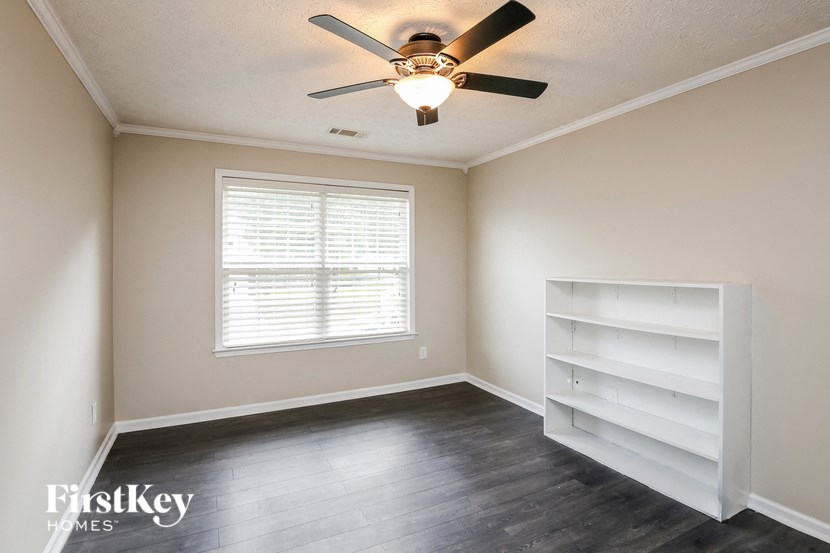 an empty room with a ceiling fan and white shelves