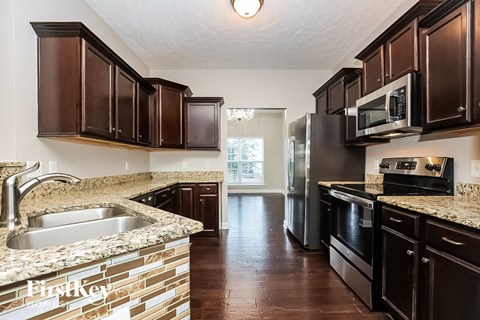 A kitchen with dark brown cabinets and a granite counter top.