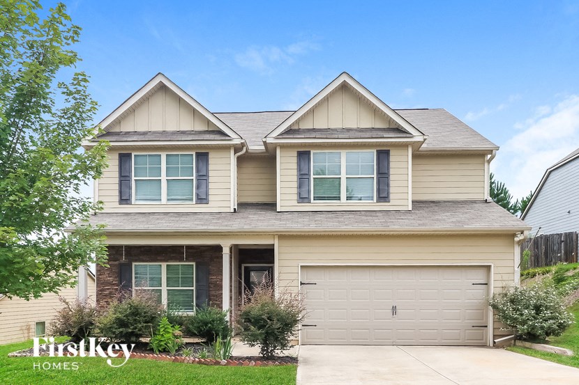 a tan house with two peaked roofs and a garage door