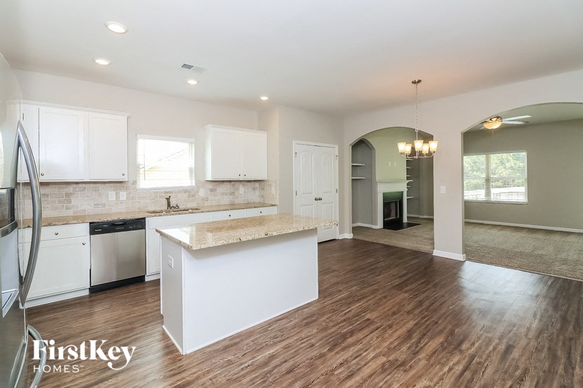 an open kitchen and living room with white cabinets and a white counter top