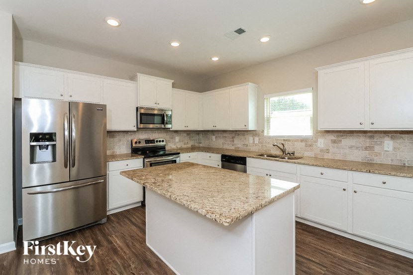 a kitchen with white cabinets and a marble counter top