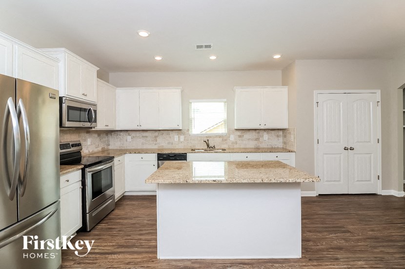 a kitchen with white cabinets and a marble counter top