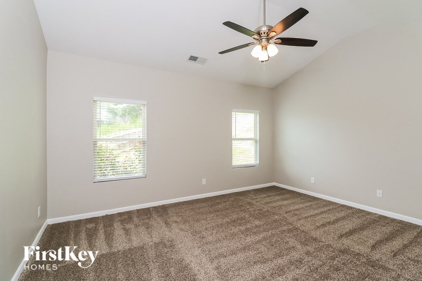 the master bedroom has a carpeted floor and a ceiling fan