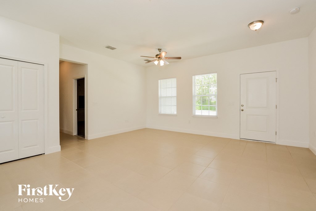 an empty living room with a ceiling fan and white doors