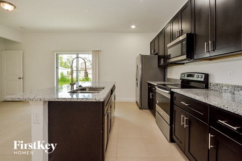 large kitchen with granite counter tops and black cabinets and stainless steel appliances
