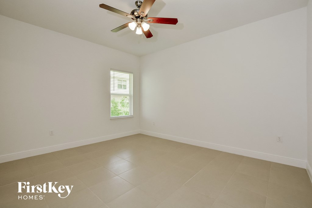 an empty room with a ceiling fan and a window