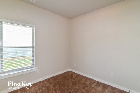 a bedroom with a large window and brown carpet