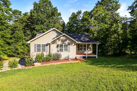 A house with a well-kept lawn and trees in the background.