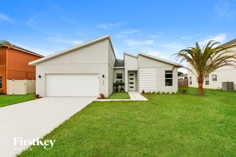 a white house with a lawn and a palm tree