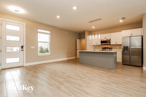 an open kitchen and living room with stainless steel appliances and wooden floors