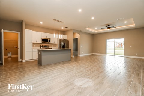 an empty living room with a kitchen and a door to the yard